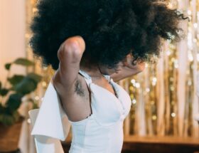black woman with curly hair putting on dress