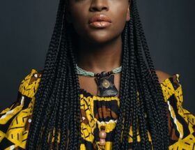 Attractive Woman with African Pigtails Hairstyle in Yellow Dress with Exotic Pattern