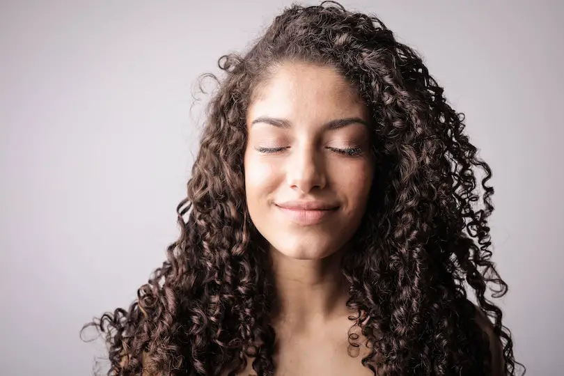 Portrait Photo of Smiling Woman with Brown Curly Hair with Her Eyes Closed